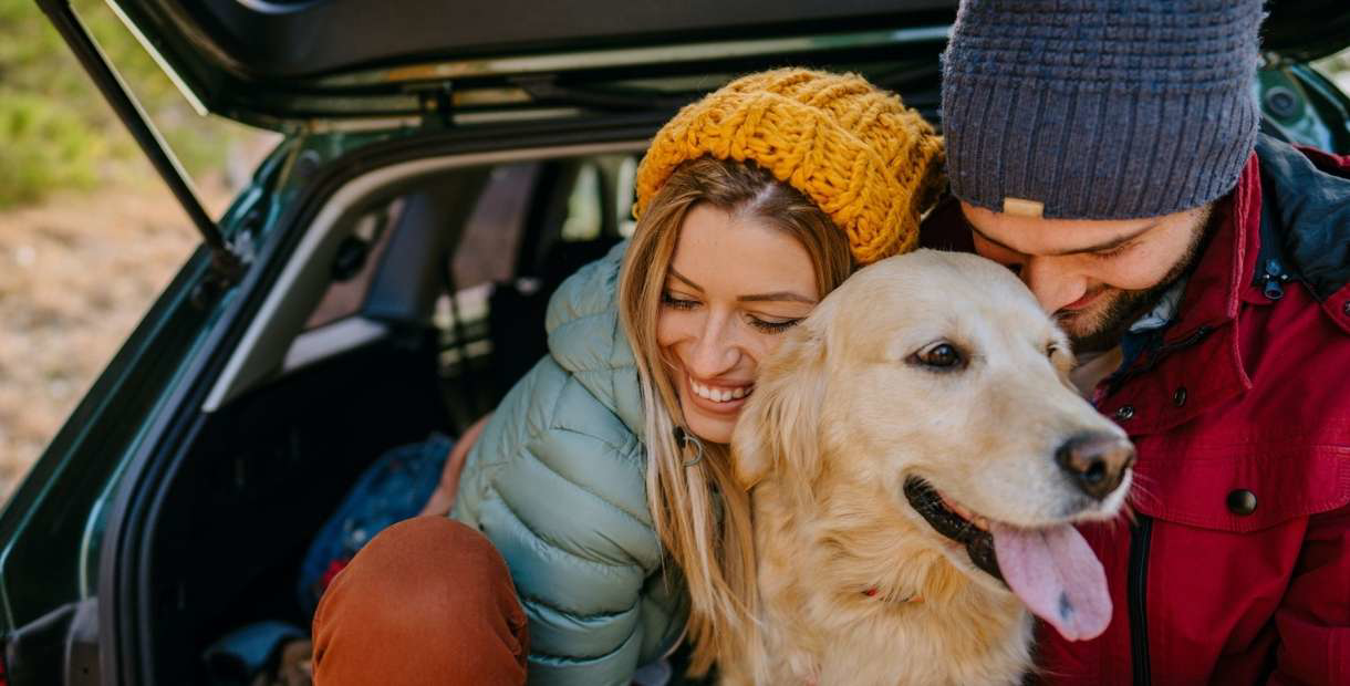 A woman and her dog sitting in the back of a hatchback.