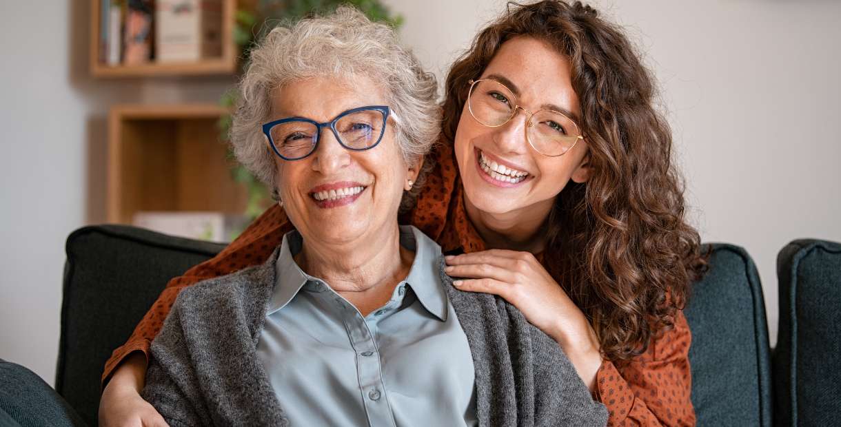Two people smiling sitting on a couch.