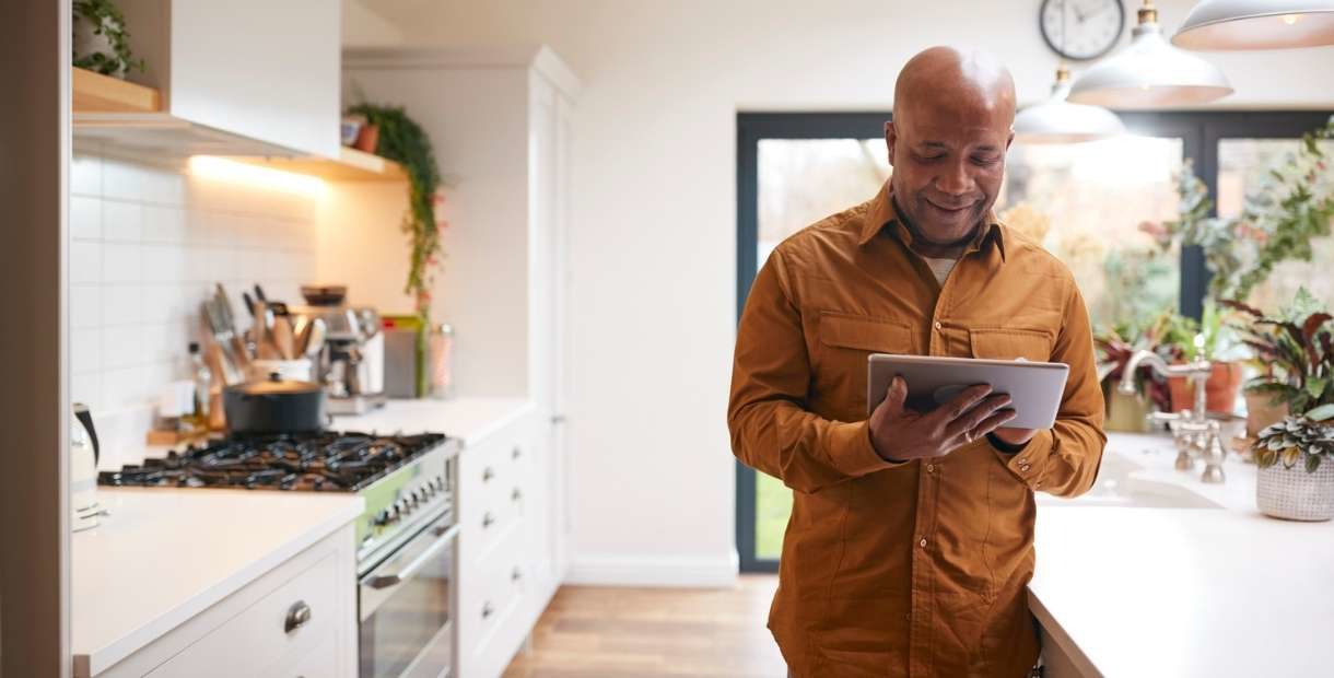 Empty nester standing in a modern kitchen, using a tablet to explore financial tips for the next stage of life.