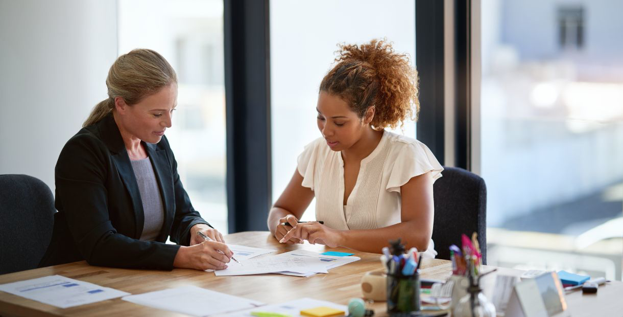 two people sitting at a table working on paperwork.