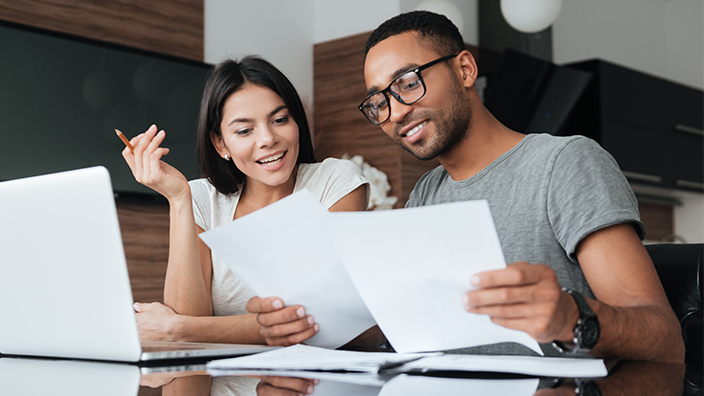 A man and woman in their home looking over papers. 