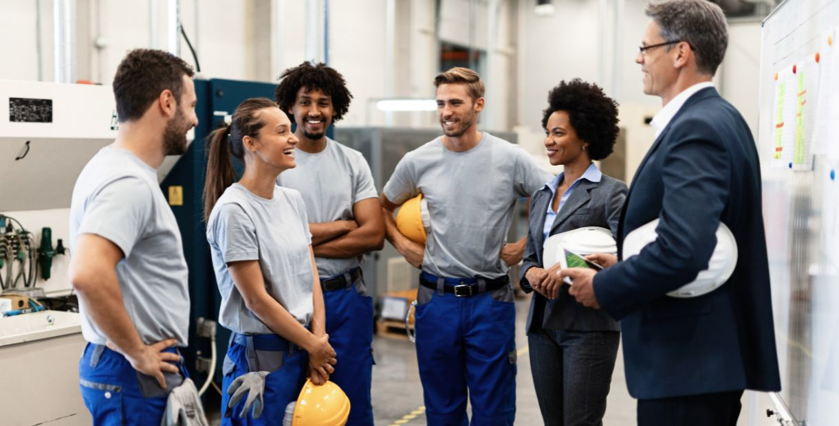 A group of employees in a factory talking to an executive.