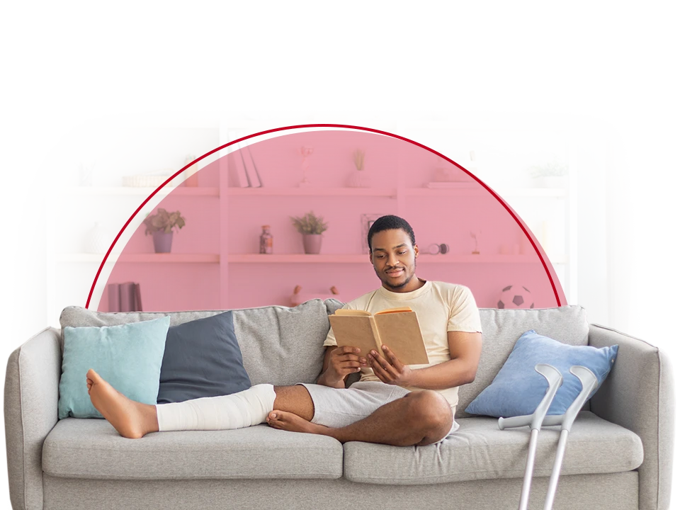 Young man on couch with crutches nearby.