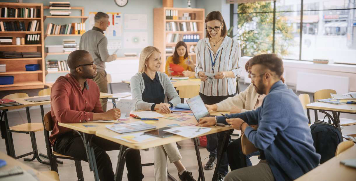 Teacher standing in a classroom with coworkers.