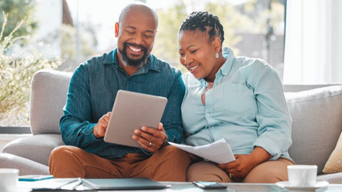 A mature couple looking through paperwork while using a digital tablet