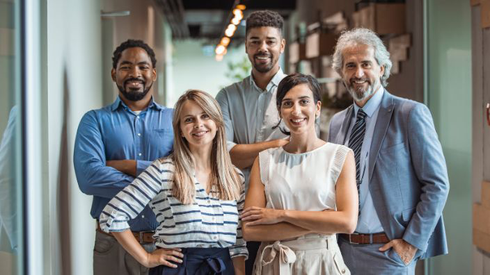 Group of well-dressed colleagues standing together and smiling. 