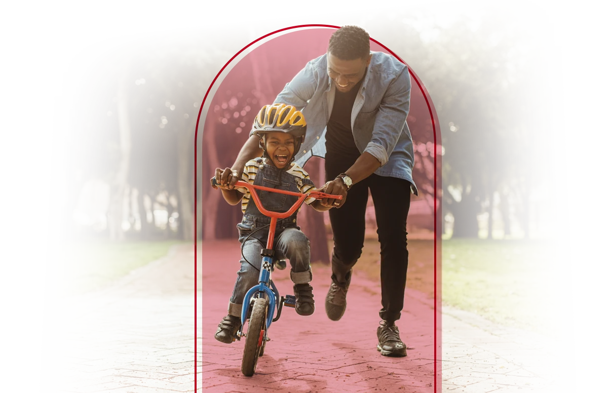 Father helping his child ride a bike.