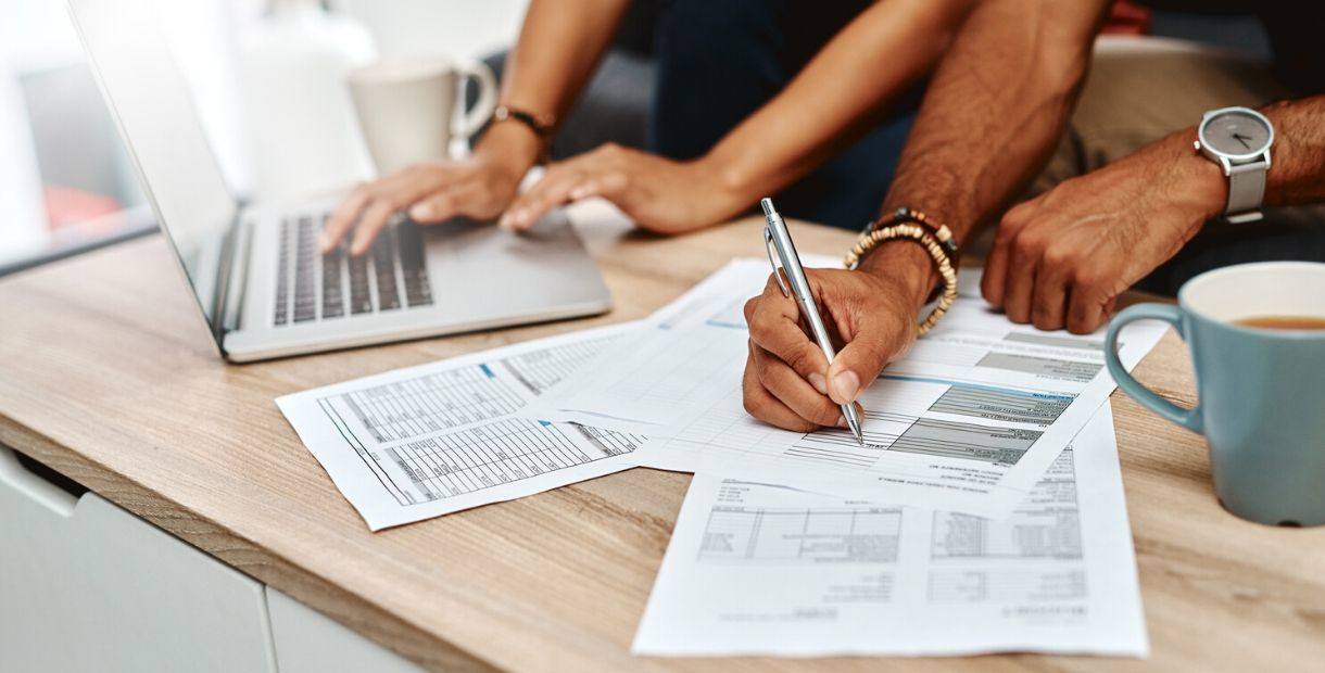 Two people working together on financial documents at a table.
