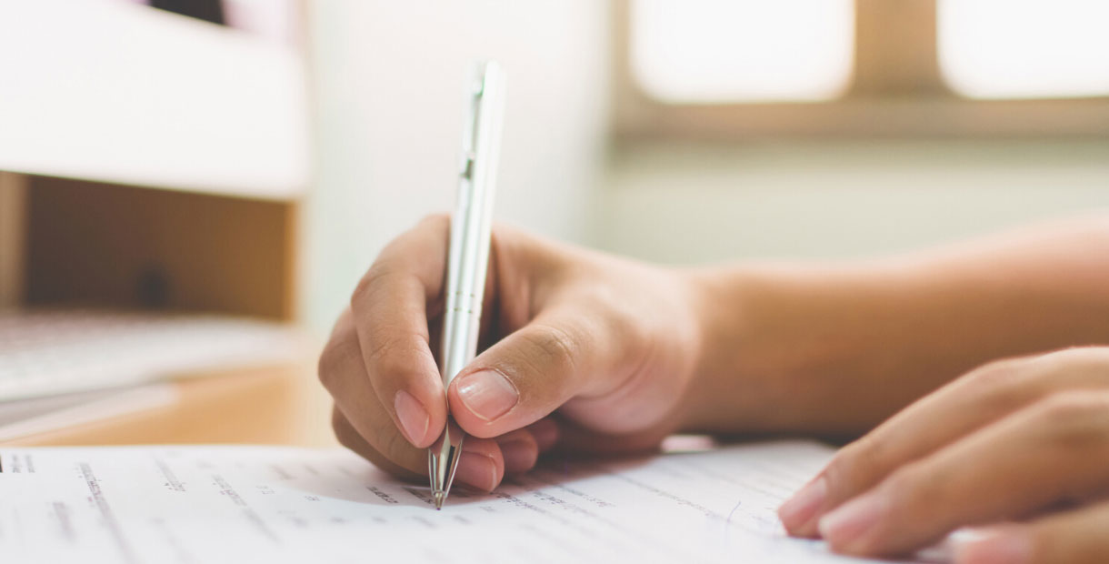 A camera shot focused on a woman's hands, filling out a disability claim form.