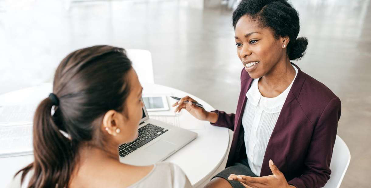 Two women in an office discussing retirement withdrawals vs loans.
