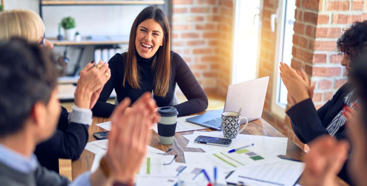 a group of business people clapping at a meeting.