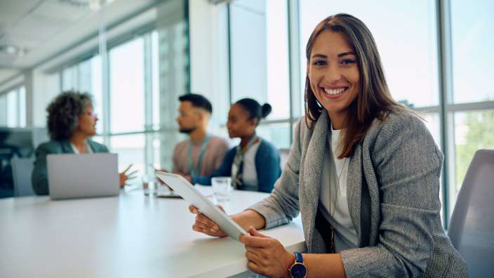 An HR professional holding a tablet during a meeting with colleagues. 