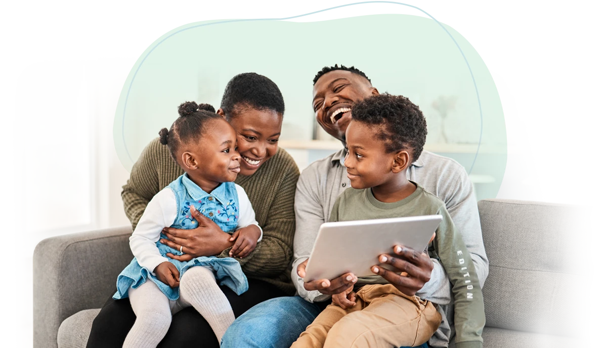 Happy young family on the sofa looking at their tablet computer