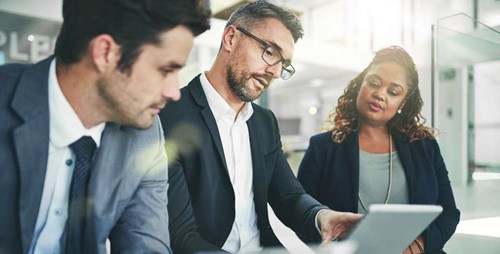 Three business professionals reviewing documents.