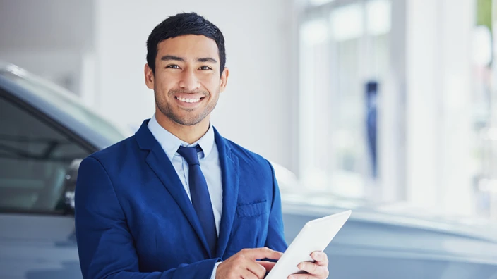 A young man with a clipboard in his hand standing in front of an SUV.