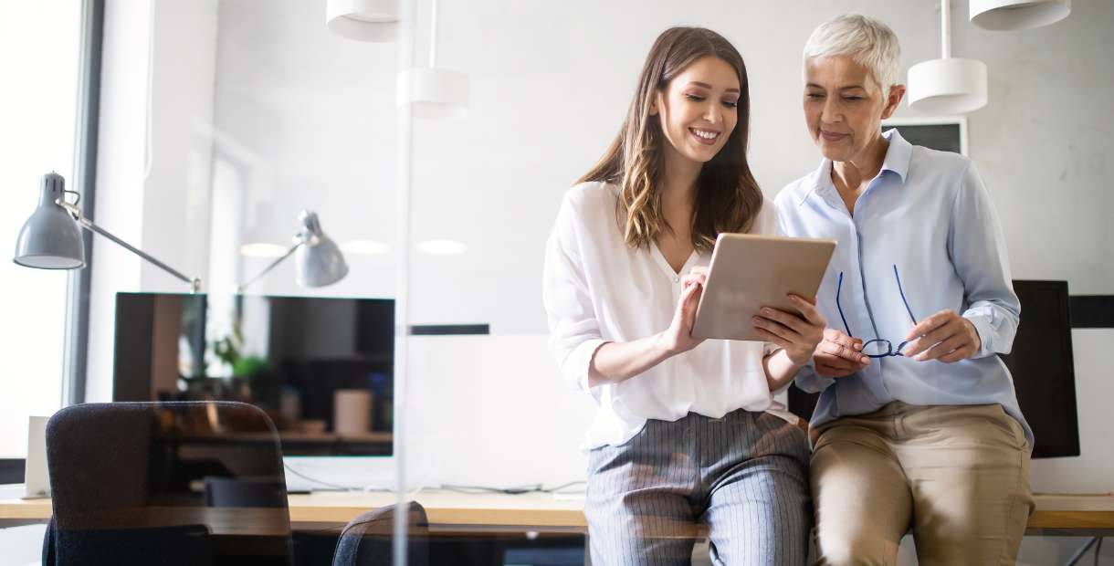 Two woman reviewing documents smiling.