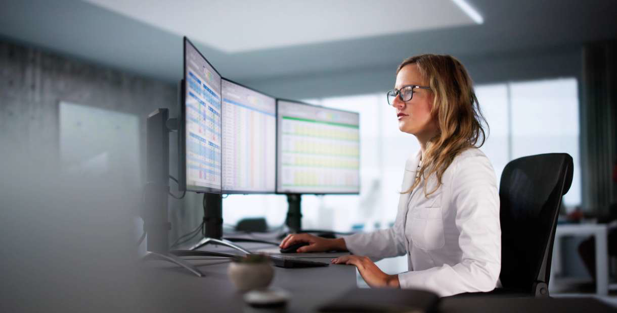 HR manager sitting at a desk in front of two computer monitors.