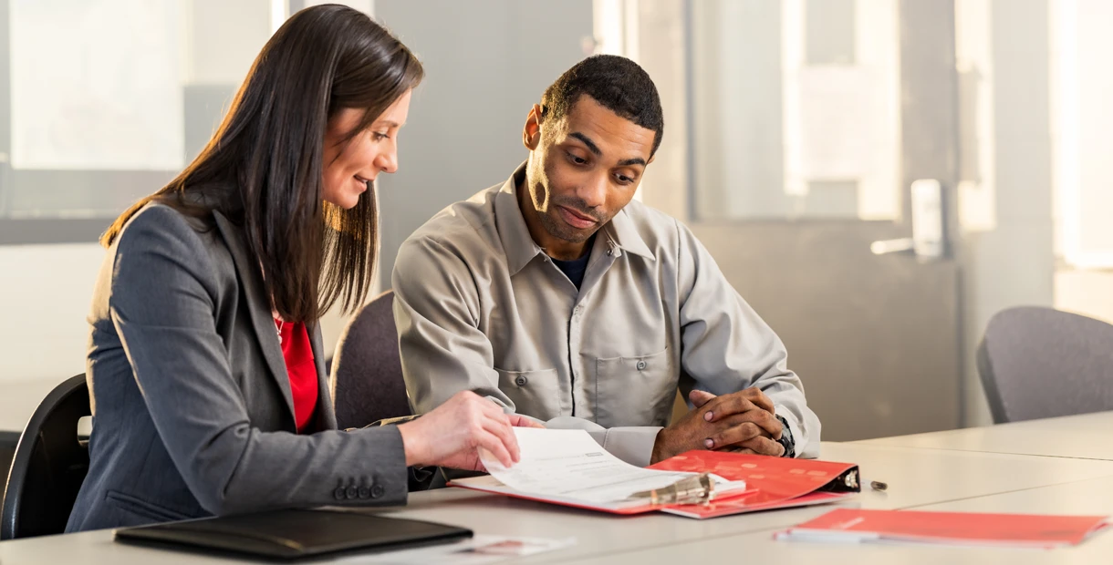 A man and a woman discussing policies on a clipboard.