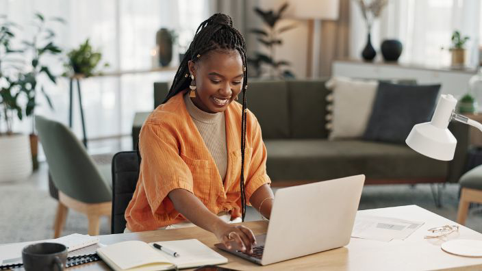 A girl in a yellow blouse smiling while typing on a computer.
